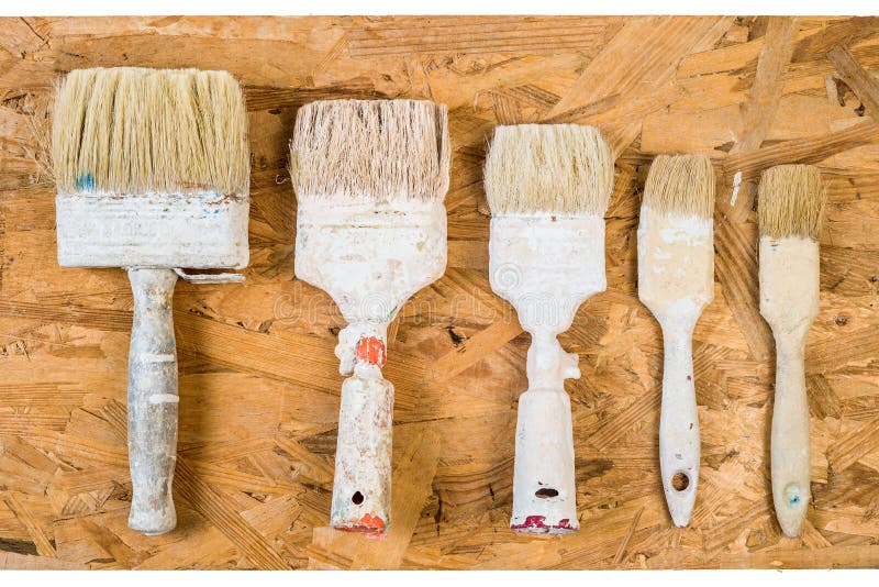 Old used brushes on OSB surface. Five old used brushes with bits of dried white paint on OSB background royalty free stock photos